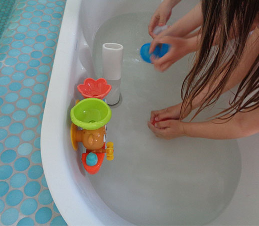 Kind spielt mit Wasserspielzeug in der Wanne