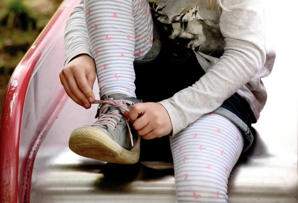 Kind bindet sich auf der Rutsche den Schuh – Selbstständigkeit in der Kita