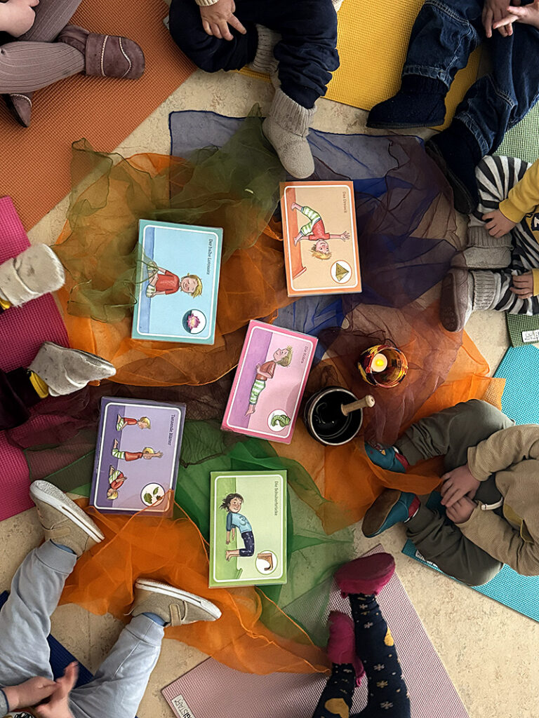 Kinder sitzen um Yogakarten – Kinderyoga in der Neuköllner Kita