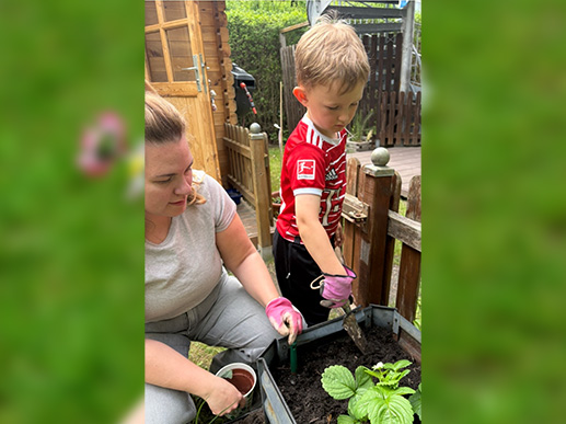 Frau und Kind bepflanzen ein Hochbeet im Kita-Garten