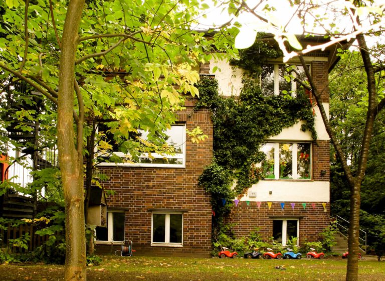 Außenansicht der Kita Schneckenhaus mit begrüntem Gebäude und Garten